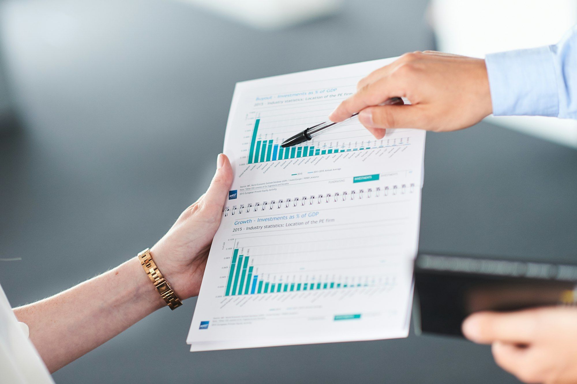 An advisor and client reviewing a financial report with bar charts at a desk