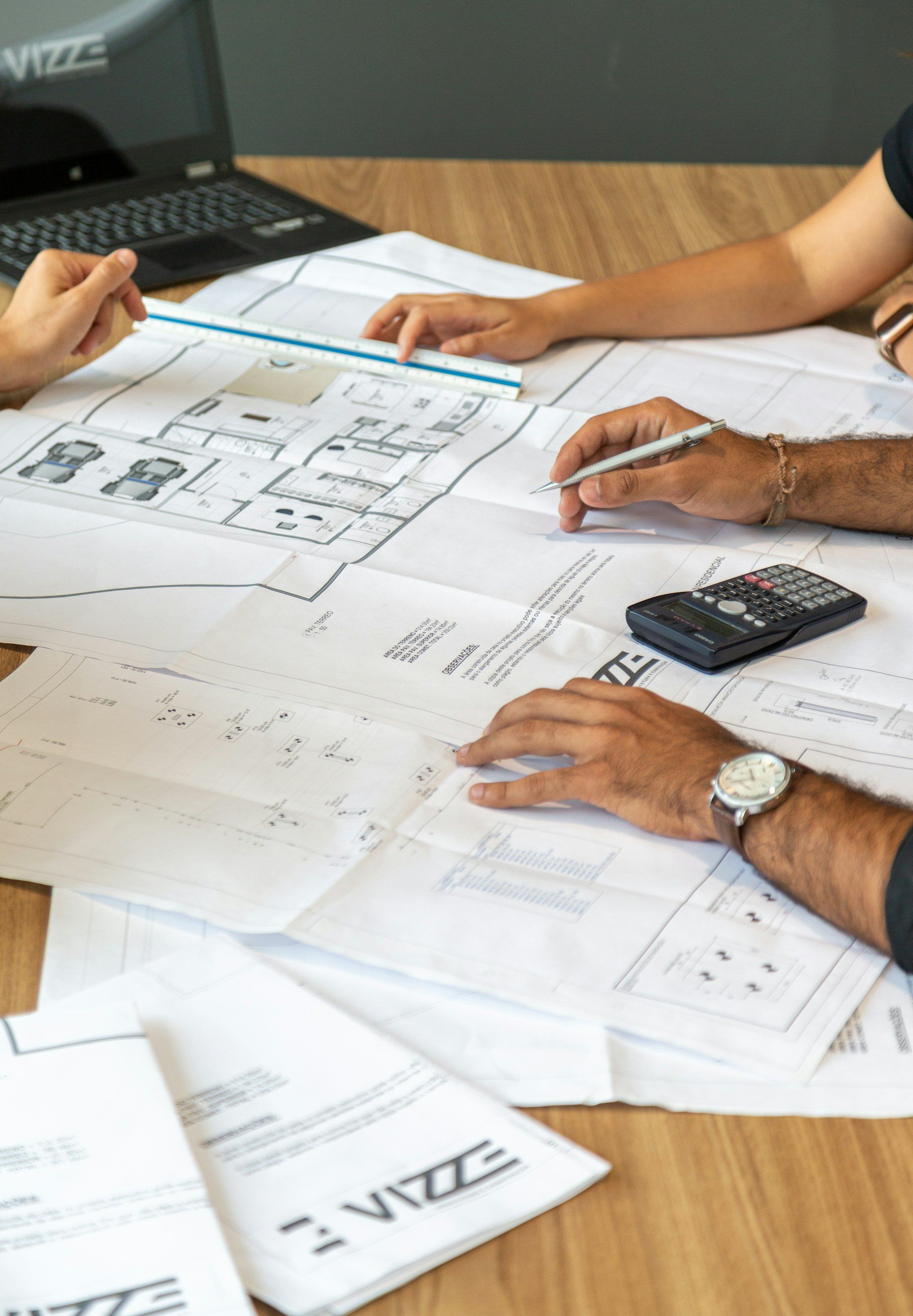 Architects reviewing printed building plans and blueprints together on an office desk