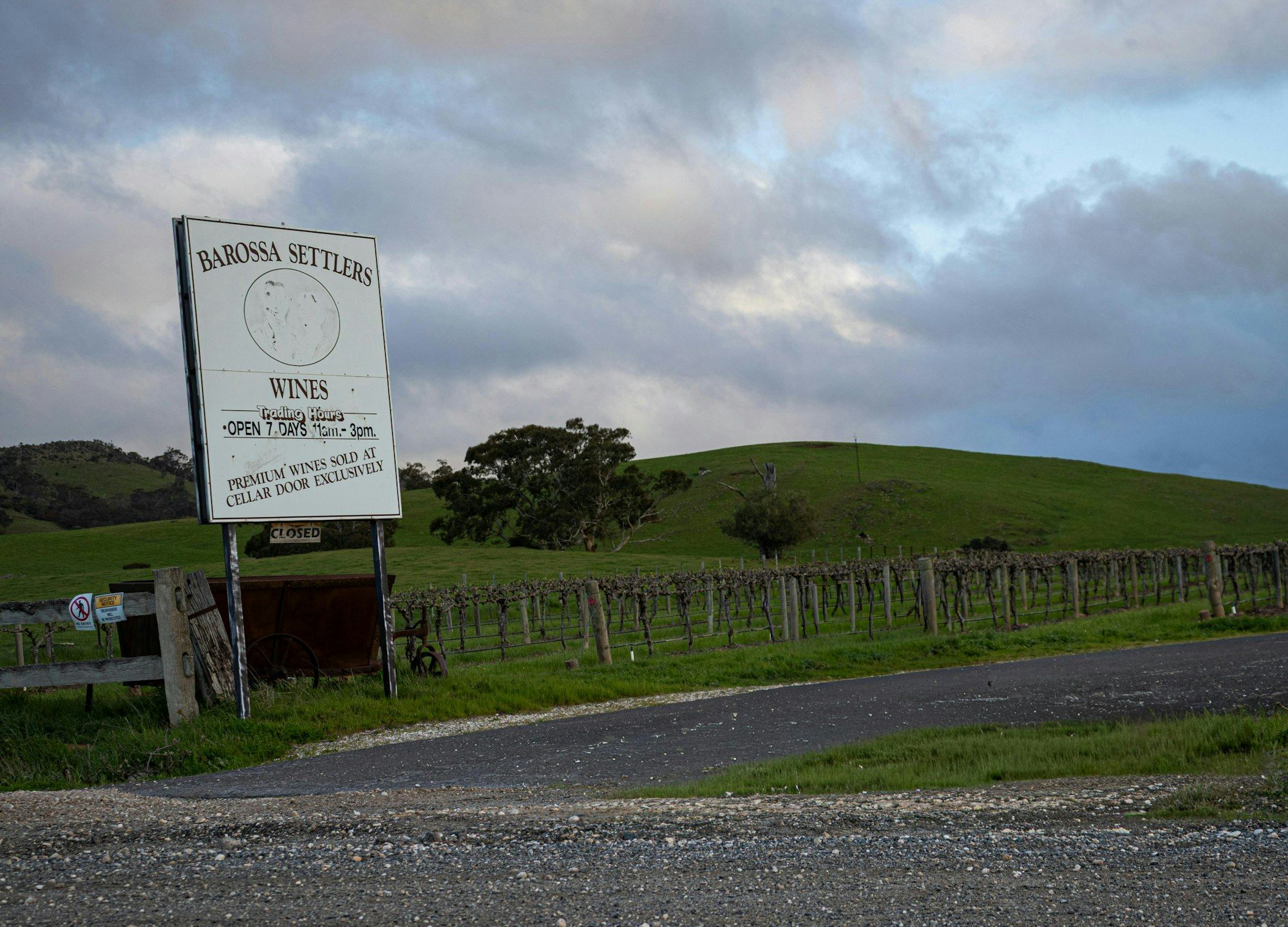 Winery entrance sign with rows of grapevines and rolling hills in the Barossa Valley