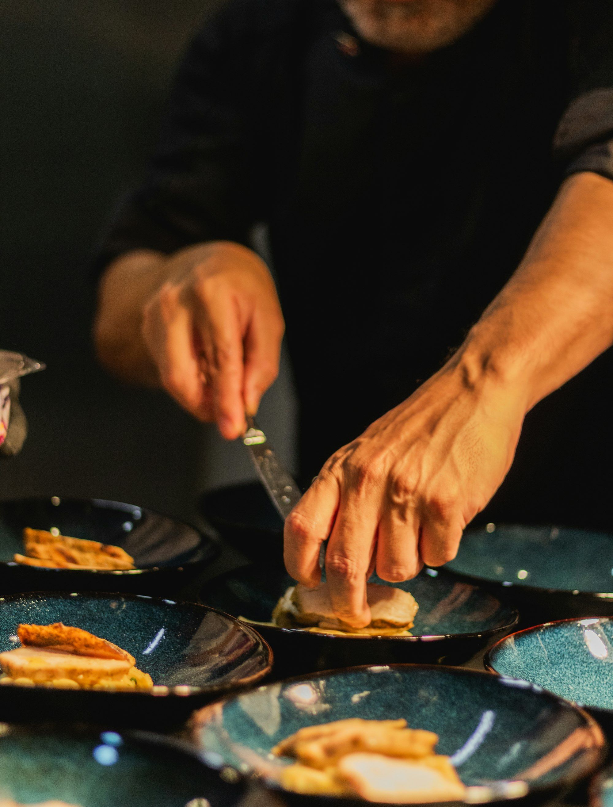A chef carefully finishing plates at the pass, ready to go out during service