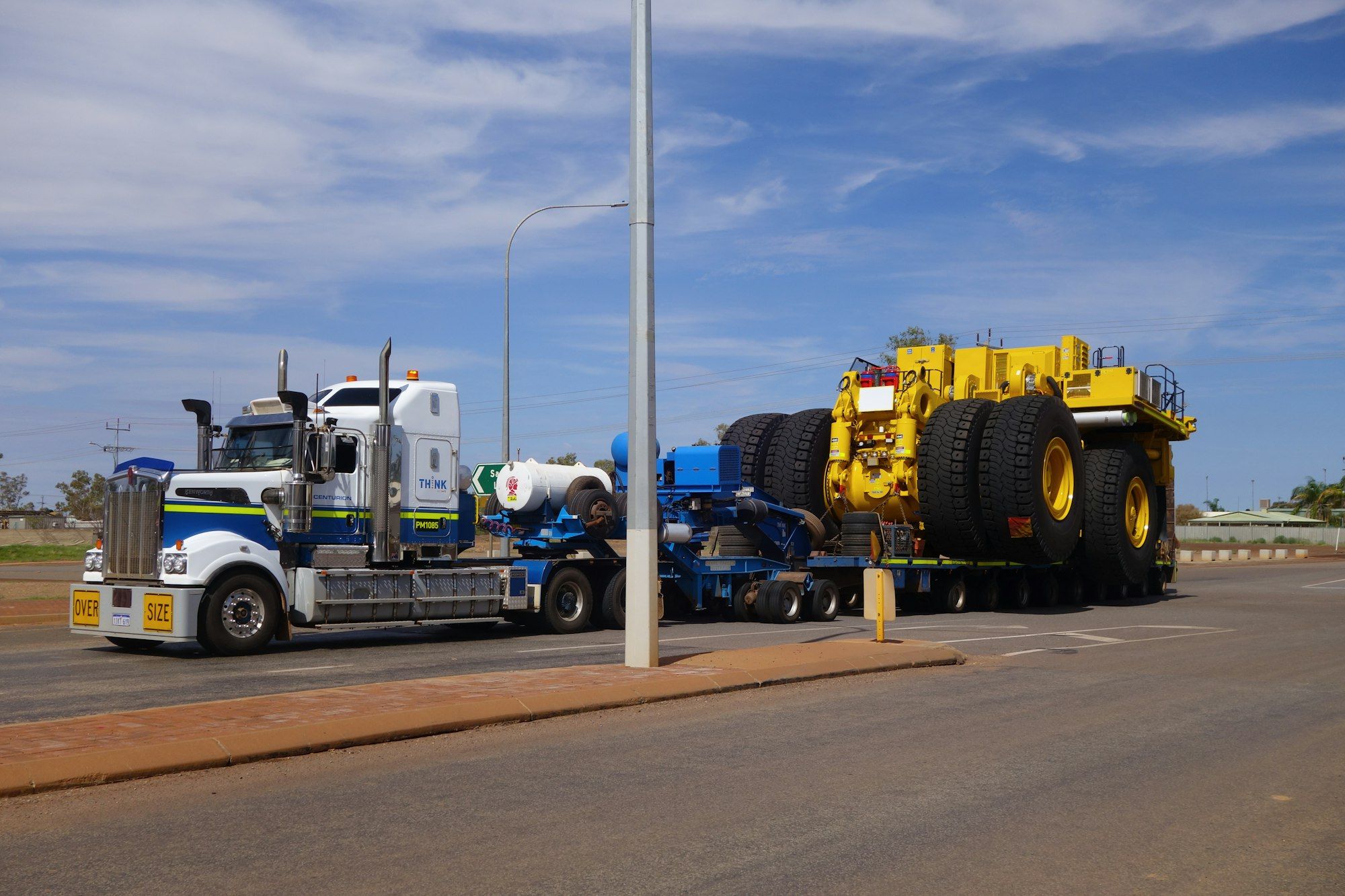 A semi-trailer hauling an oversized yellow mining truck through outback Western Australia