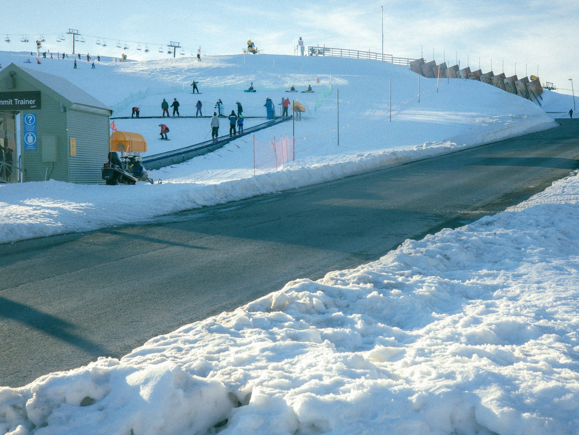 Skiers on a sunny snow-covered slope beside resort buildings at Mt Hotham, Victoria